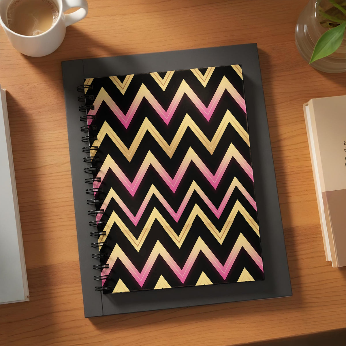 Spiral notebook with black cover featuring a pink and gold chevron pattern.
