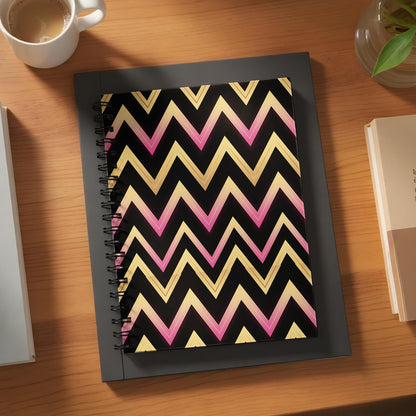 Spiral notebook with black cover featuring a pink and gold chevron pattern.