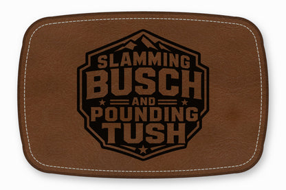 Brown leather patch with white stitching and a black stamped design reading Slamming Busch and Pounding Tush.