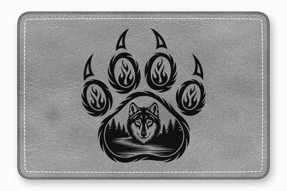 Gray textured leather patch featuring a black bear paw print enclosing a wolf and forest landscape.