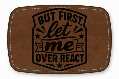 Brown leather patch with rounded corners, white stitching, and black engraved text reading But first, let me overreact.
