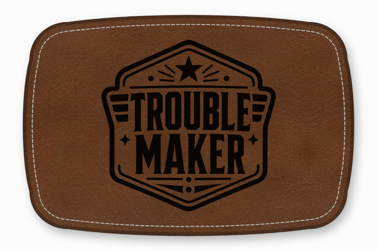 Brown leather patch with white stitching and a black emblem featuring the text TROUBLE MAKER.