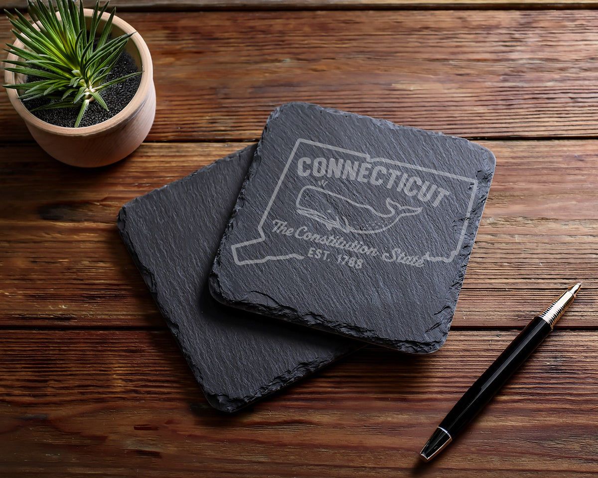 Two slate coasters, one engraved with Connecticut outline, whale, and text.