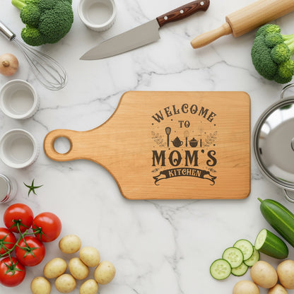 Wooden cutting board with "Welcome to Mom's Kitchen" engraved text.