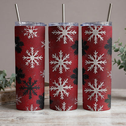 Three red tumblers with white and black snowflake patterns and silver straws.