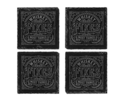 Four black slate coasters with engraved text "WHISKEY FIXES MOST THINGS" and skulls.