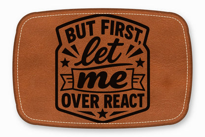 A brown leather patch with white stitched edges featuring the black text, BUT FIRST, let me OVER REACT.
