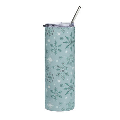 Tumbler with a blue background and a pattern of various green and white snowflakes, with a metal straw.