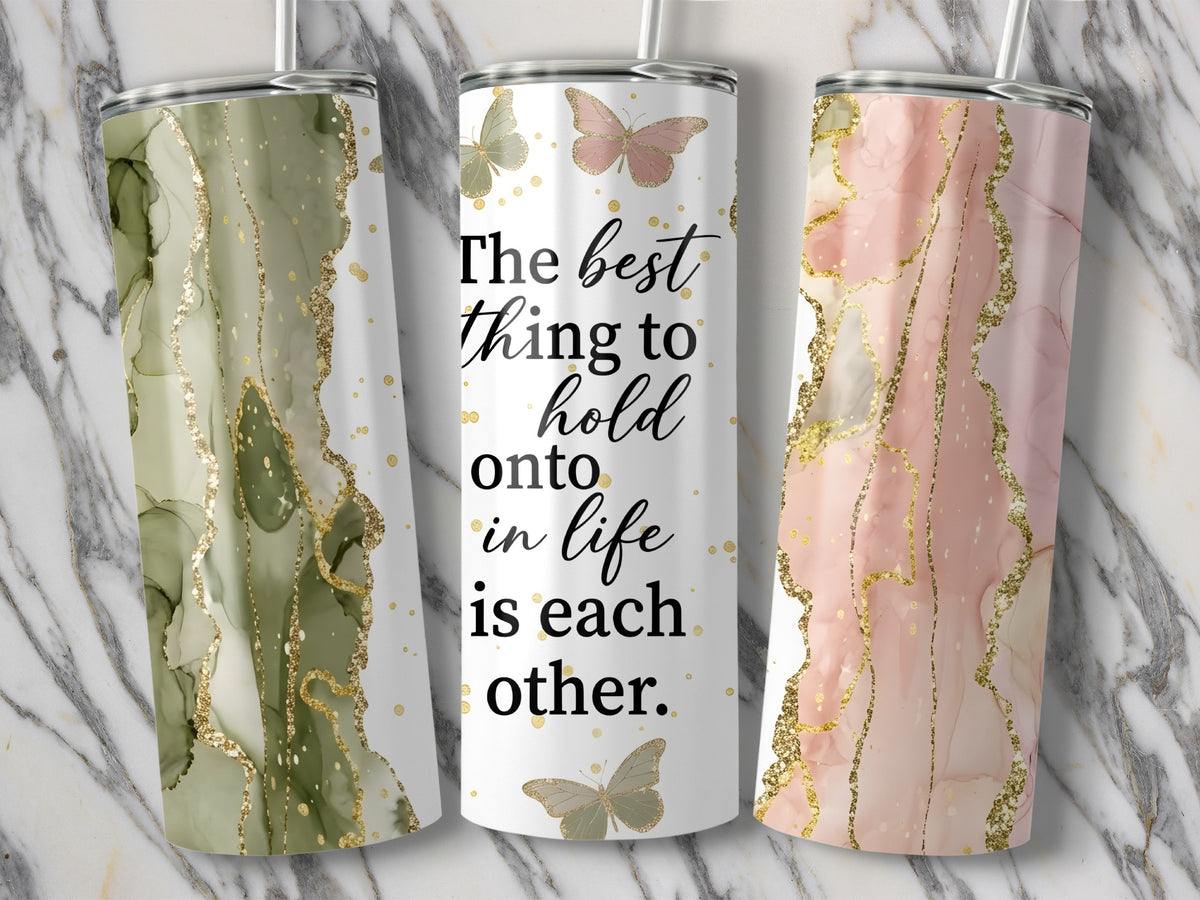 Three tumblers with marble and gold designs, center one quotes "The best thing to hold onto in life is each other."