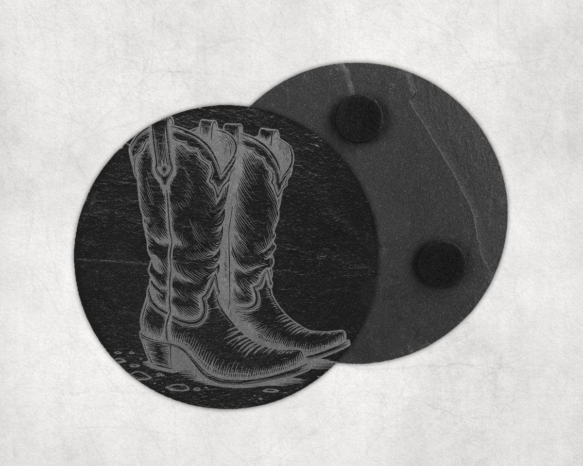 Engraved cowboy boot on a round black slate coaster, another coaster behind it.