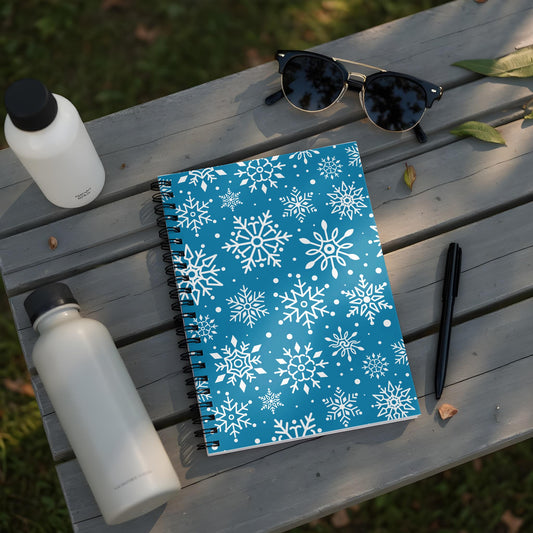 Blue spiral notebook with white snowflake pattern and black pen.
