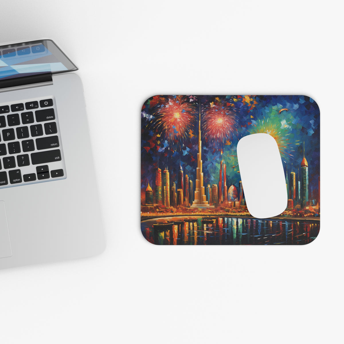 Mousepad with Dubai skyline and fireworks illustration, next to a laptop.