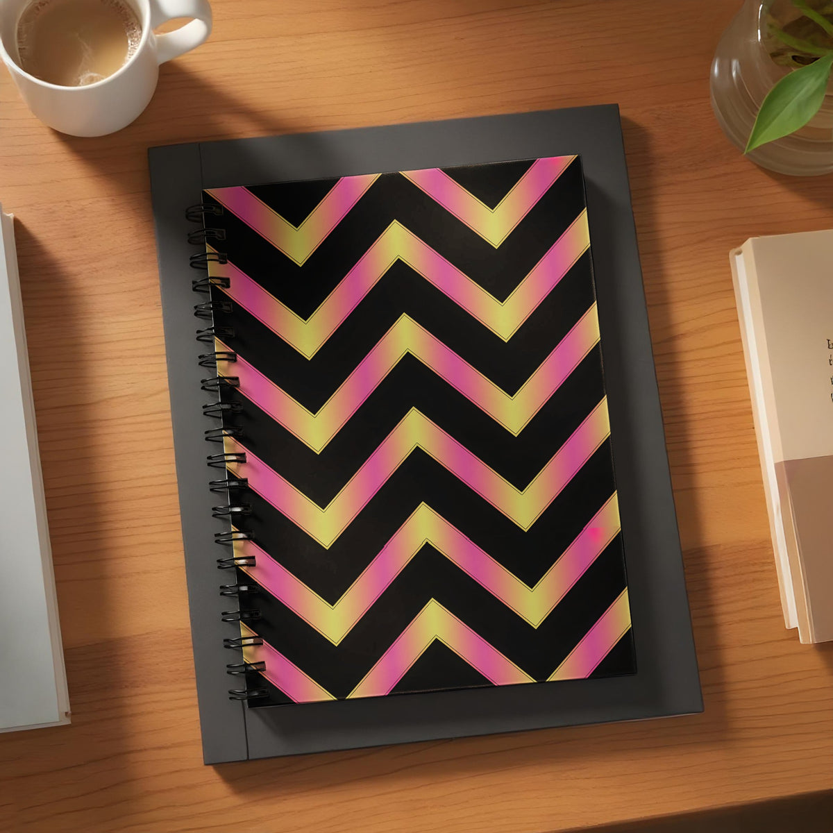 Spiral notebook with pink and yellow chevron pattern on black background.