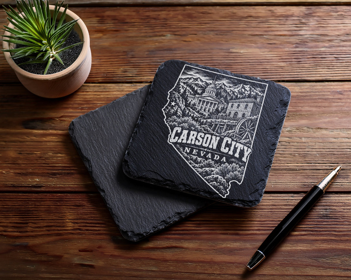 Two square black slate coasters with a Carson City Nevada engraving on a wooden table.