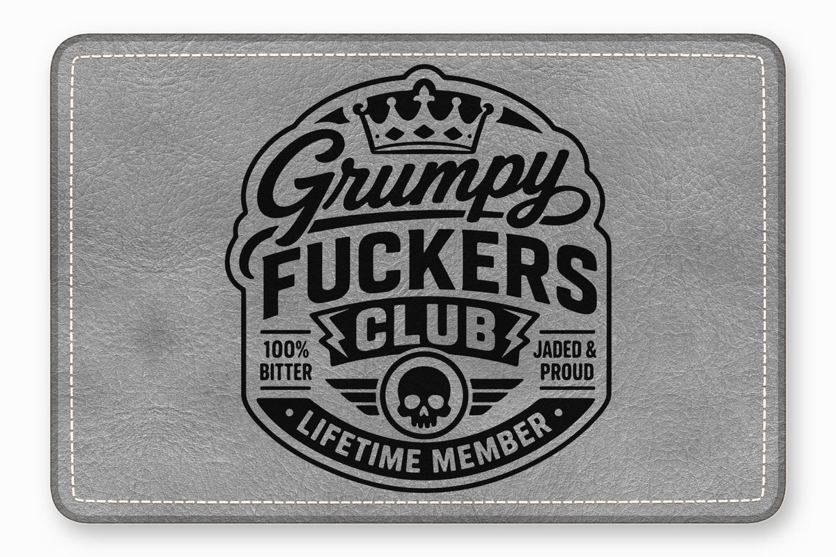 A rectangular grey leather patch featuring a black vintage-style emblem with text that reads Grumpy Fuckers Club.