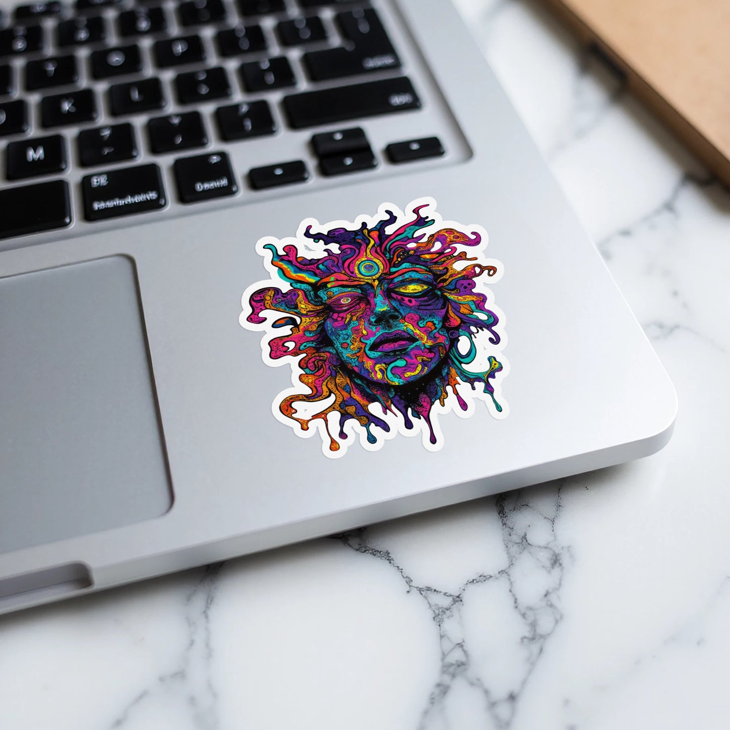 Psychedelic melting face sticker on a laptop keyboard.