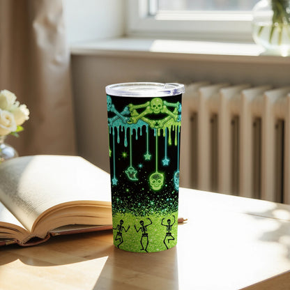 Tumbler with glowing skulls, bones, ghosts, stars, and dancing skeletons on black and green glitter background.
