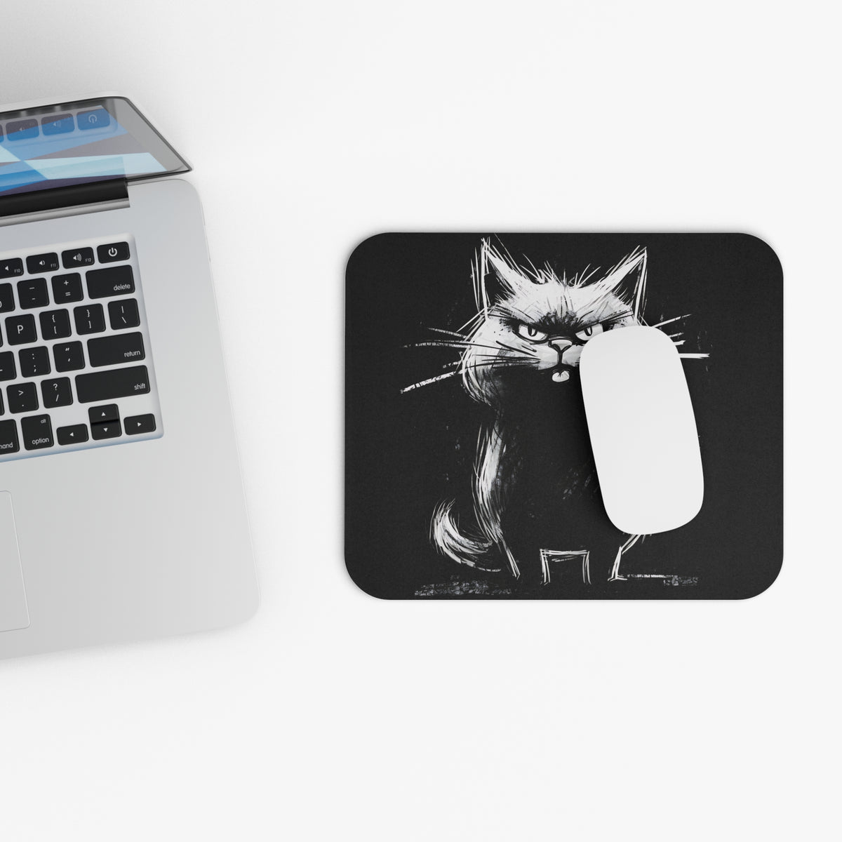 A white computer mouse rests on a rectangular black mousepad featuring a white sketchy cat illustration next to a laptop.