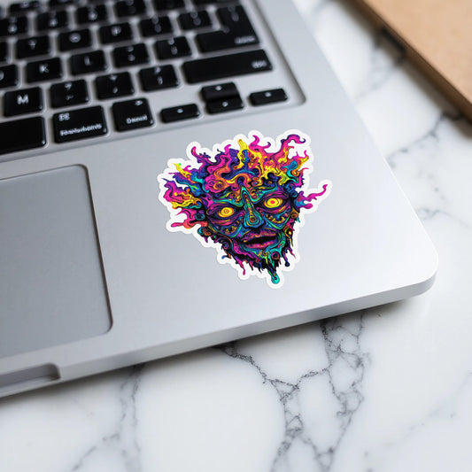 Colorful, psychedelic face sticker with yellow eyes on a laptop keyboard.