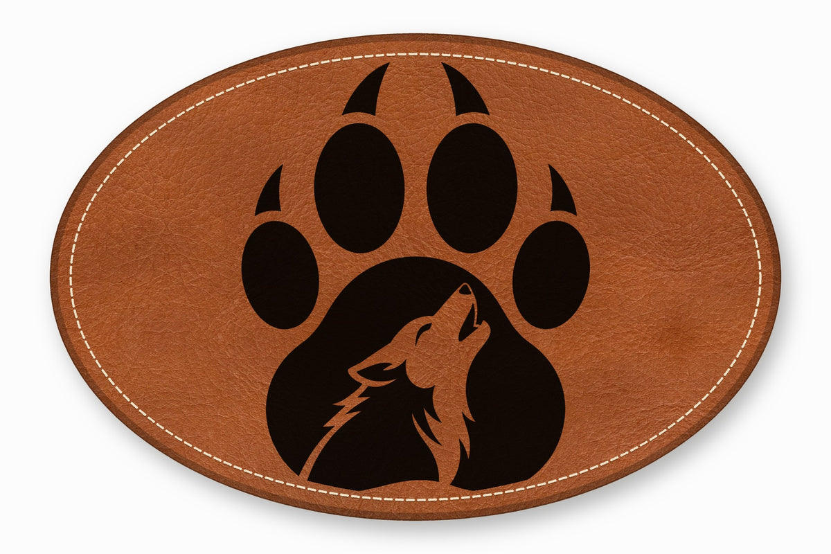 An oval brown leather patch featuring white stitching and a black paw print containing a howling wolf silhouette.