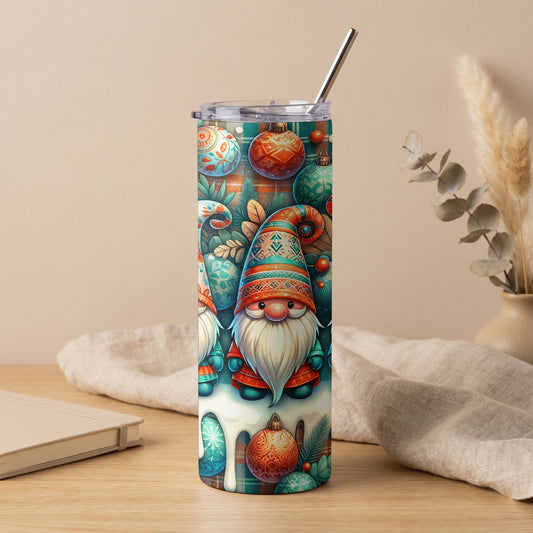 A tall tumbler with a Christmas gnome and ornament pattern, clear lid, and metal straw, standing on a wooden surface.
