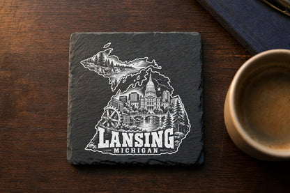 Square black slate coaster engraved with a white Michigan map outline, Lansing city landmarks, and text.