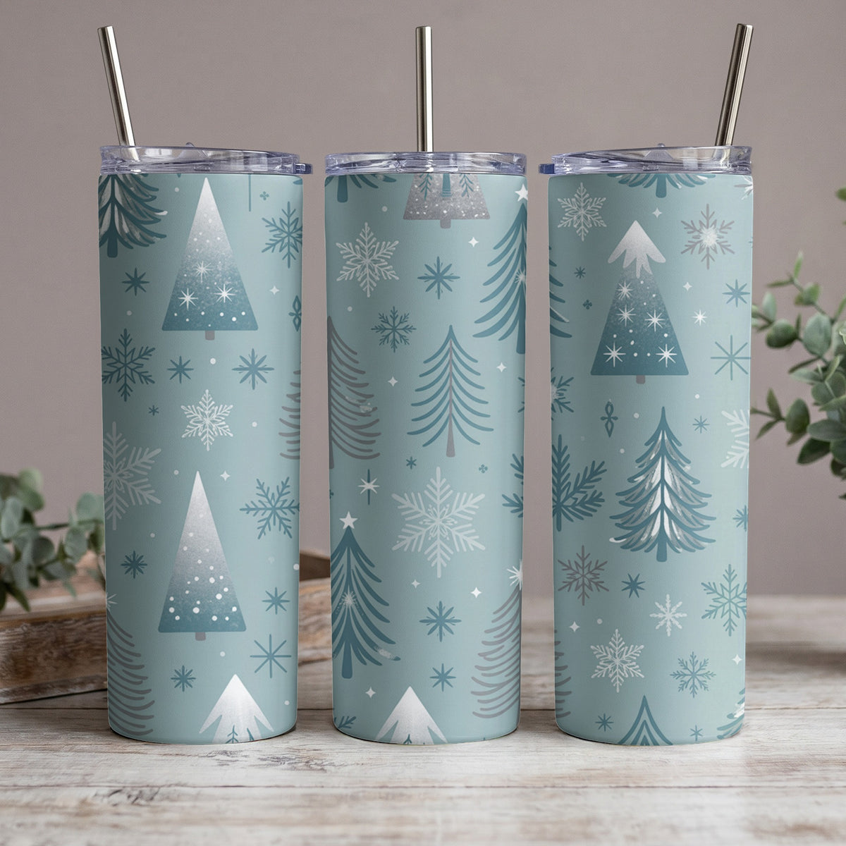 Three tumblers with a blue background and white and gray winter trees and snowflakes pattern.