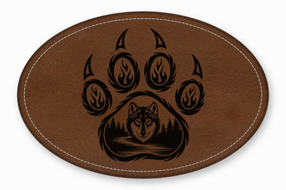 Oval brown leather patch with white stitched border and a black wolf and bear paw graphic.