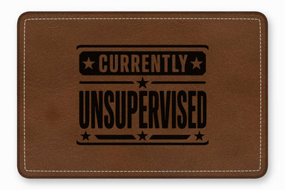 Rectangular brown leather patch with white stitched border and the black text Currently Unsupervised.