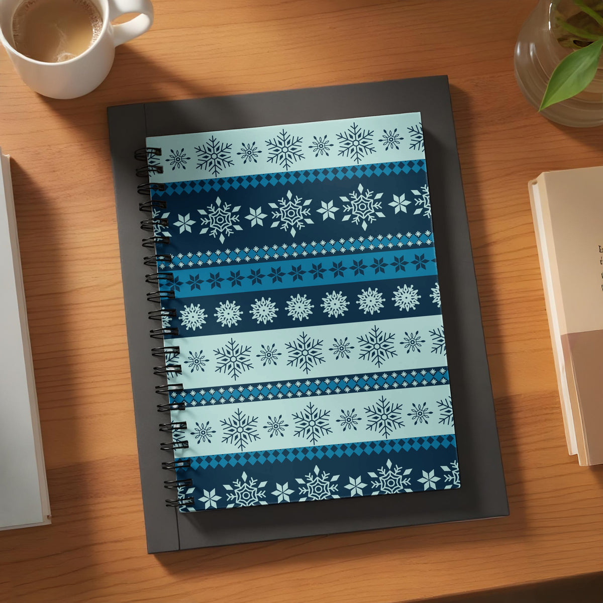 Spiral bound notebook with a repeating snowflake pattern in blues and whites.