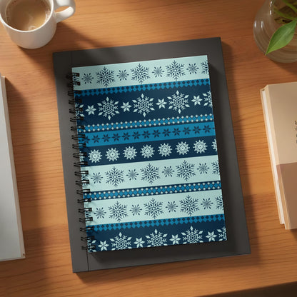 Spiral bound notebook with a repeating snowflake pattern in blues and whites.
