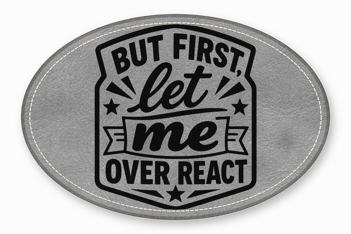 An oval gray faux leather patch with white stitched edges and black text reading "BUT FIRST, let me OVER REACT".