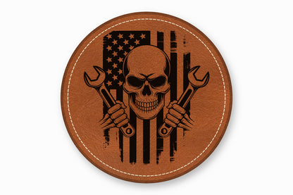 Round brown leather patch with a skull holding crossed wrenches over an American flag graphic.