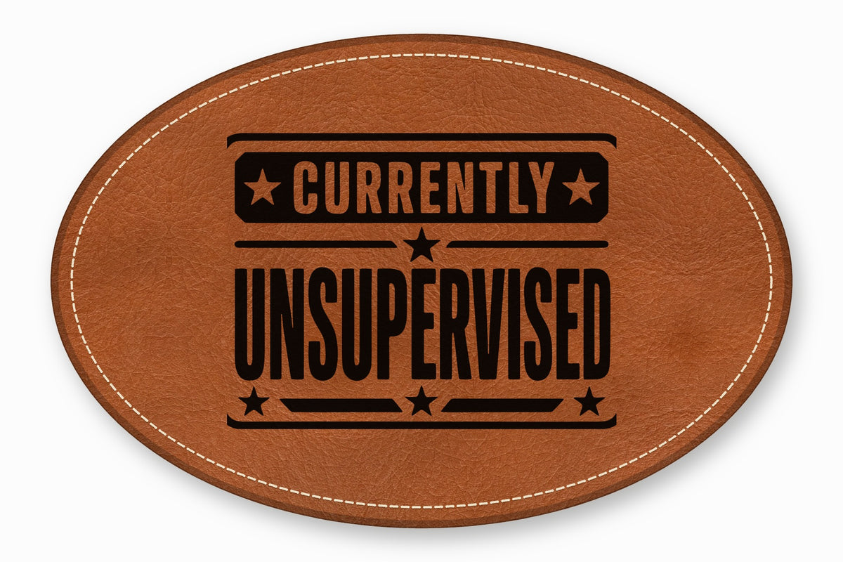 An oval brown leather patch featuring white decorative stitching and the black text currently unsupervised.