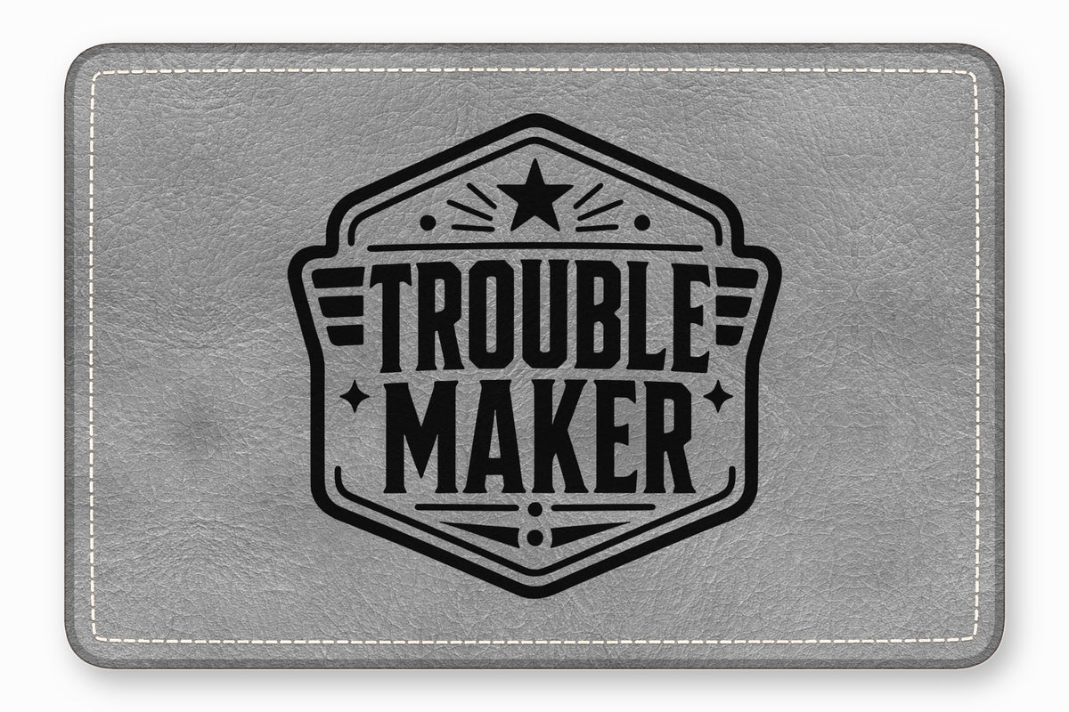 Gray leather patch with white stitched borders and a black emblem featuring the text Trouble Maker.