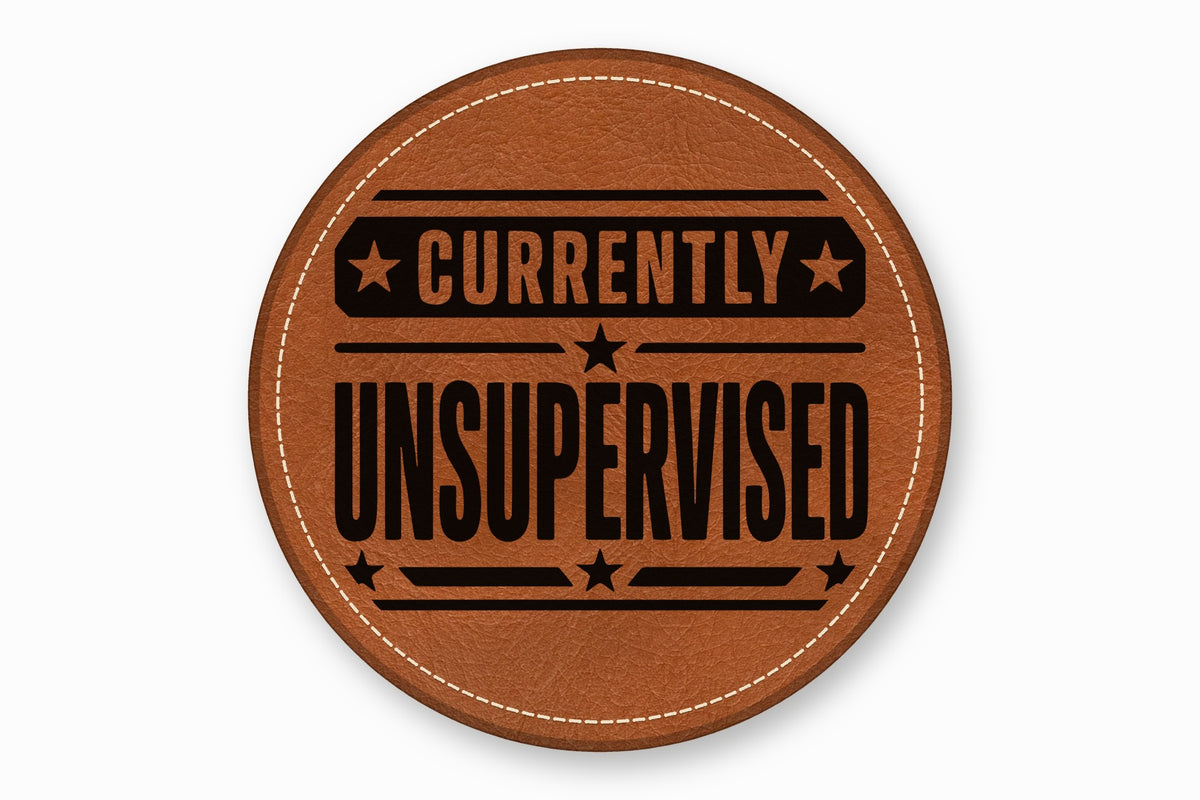 A round brown leather patch with white stitched edges and black text reading Currently Unsupervised.