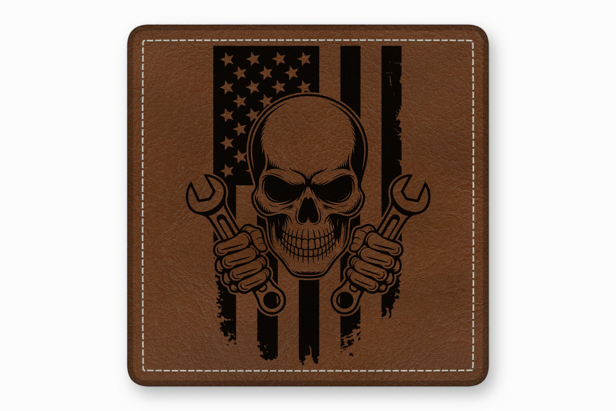Brown leather patch with rounded corners featuring a skull holding two wrenches over an American flag design.