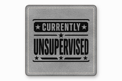 Grey leather patch with white stitched border and black text reading Currently Unsupervised surrounded by stars.