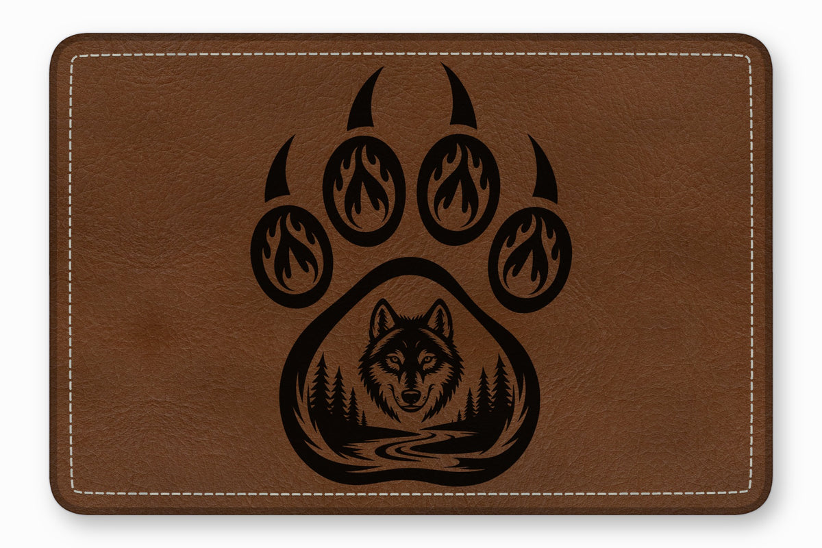 Brown rectangular leather patch with white stitched border and a black laser-engraved bear paw and wolf design.