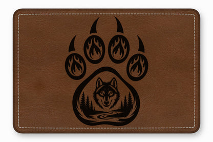 Brown rectangular leather patch with white stitched border and a black laser-engraved bear paw and wolf design.