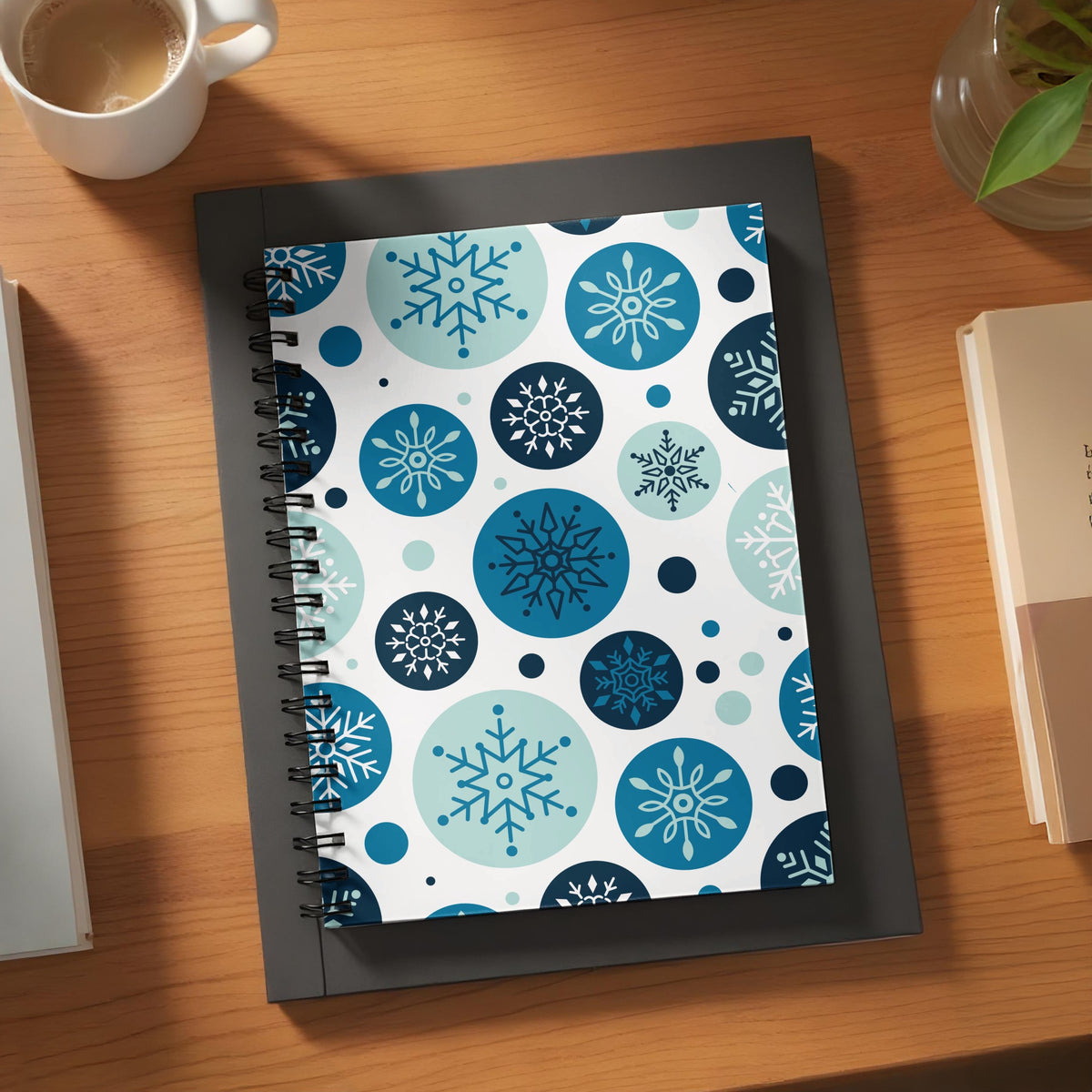 Spiral-bound notebook with a white cover featuring a pattern of blue and teal snowflakes within circles.