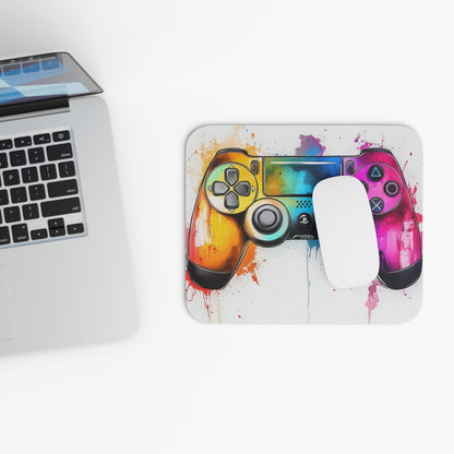 Gaming controller with watercolor splash design on a mousepad next to a laptop.