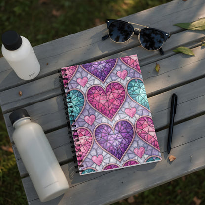 Notebook with stained glass heart pattern, sunglasses, and water bottles on a wooden surface.