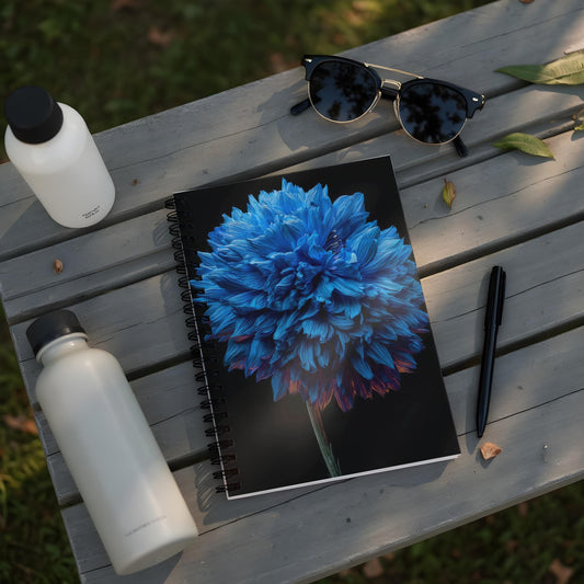 Spiral notebook with blue flower cover, water bottles, sunglasses, and pen on a wooden bench.