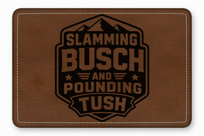 A rectangular brown leather patch with white stitched borders and a black laser-engraved mountain emblem reading Slamming Busch and Pounding Tush.