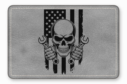 Grey leather patch featuring a black graphic of a skull holding two wrenches over an American flag.