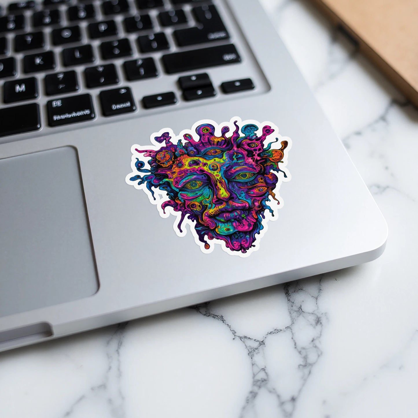 Colorful abstract face sticker with many eyes on a laptop keyboard