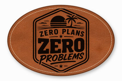 Oval brown leather patch with white stitched border, featuring a black tropical sunset emblem and the text Zero Plans Zero Problems.