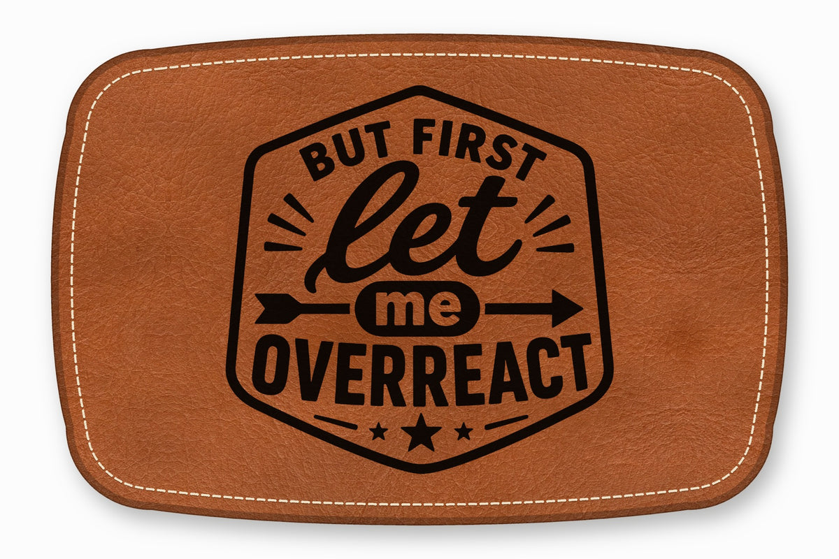 Brown leather patch with rounded corners, white perimeter stitching, and black text that reads But First Let Me Overreact.