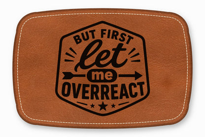 Brown leather patch with rounded corners, white perimeter stitching, and black text that reads But First Let Me Overreact.